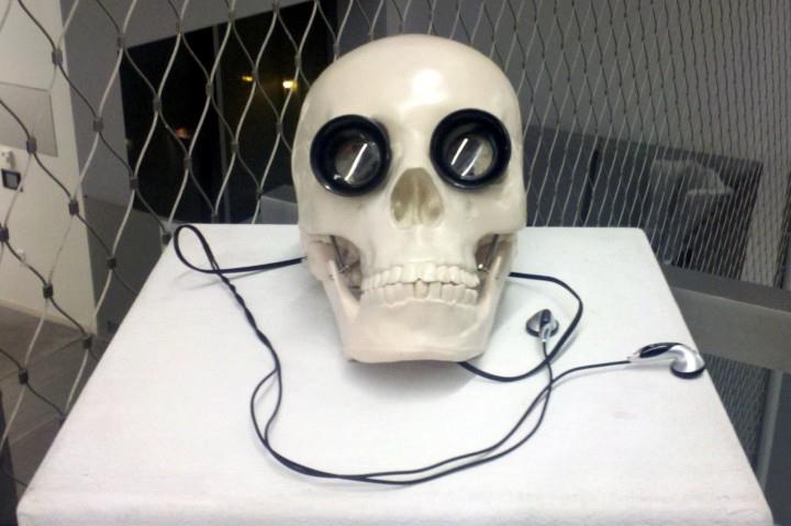 Skull with jeweler's loupes in eyes, headphones coming from the base